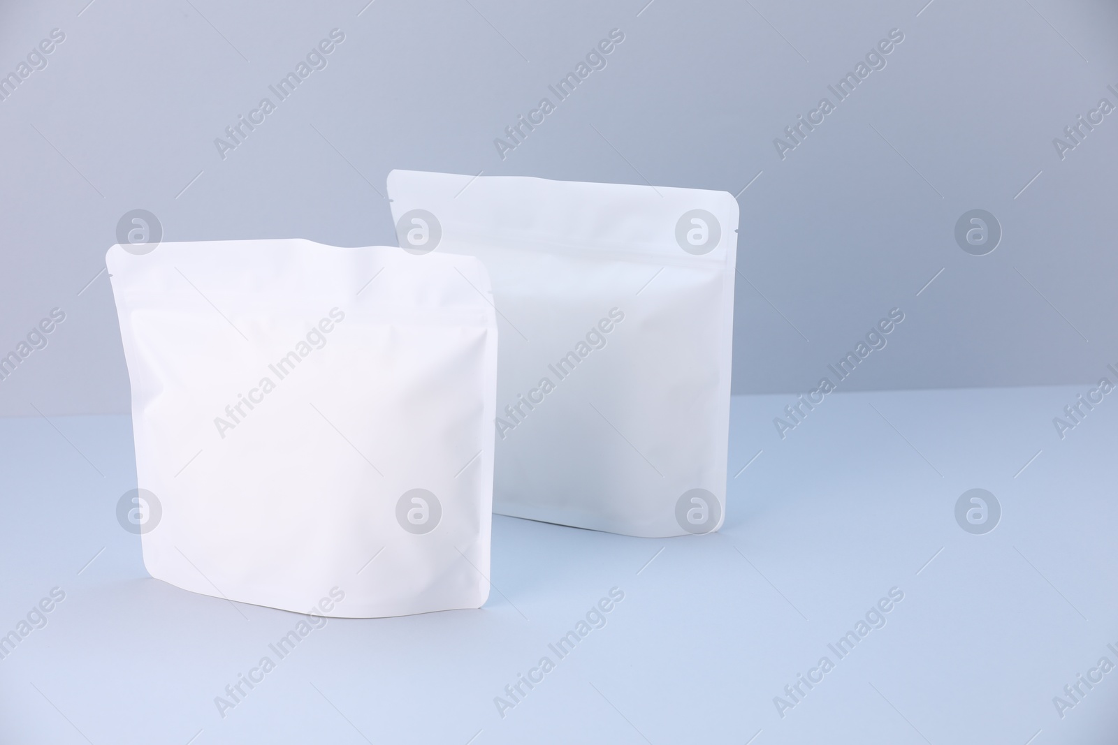 Two zipper stand-up pouches on light grey background. Mockup for design Photo of Two zipper stand-up pouches on light grey background. Mockup for design