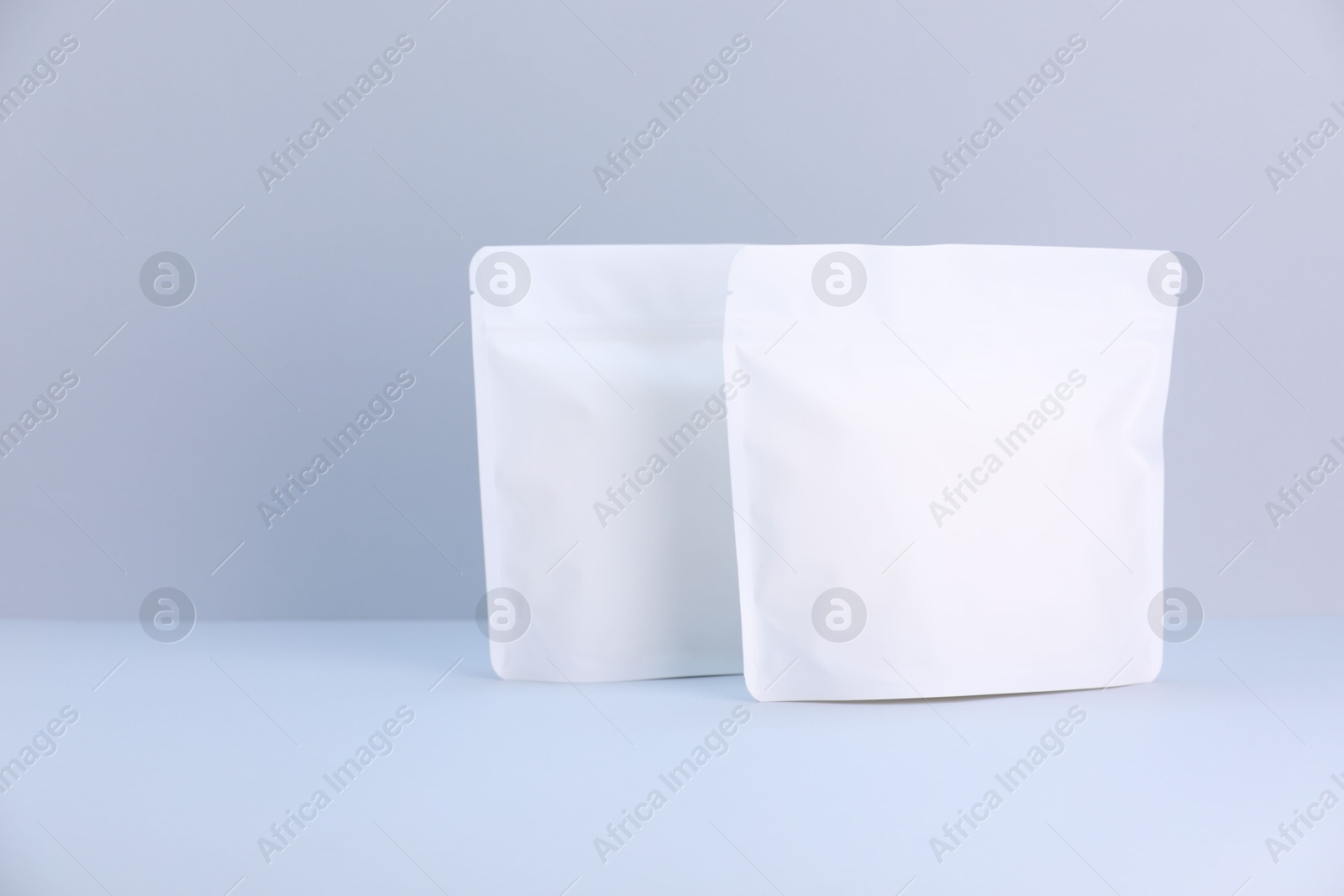 Two zipper stand-up pouches on light grey background. Mockup for design Photo of Two zipper stand-up pouches on light grey background. Mockup for design