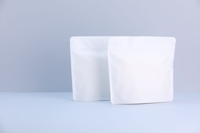 Photo of Two zipper stand-up pouches on light grey background. Mockup for design