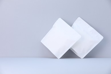 Photo of Two zipper stand-up pouches on light grey background. Mockup for design