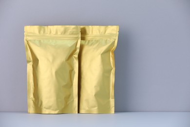 Photo of Two zipper stand-up pouches on light grey background. Mockup for design
