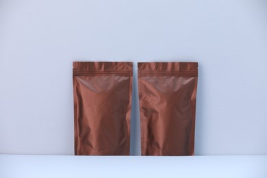 Photo of Two zipper stand-up pouches on light grey background. Mockup for design