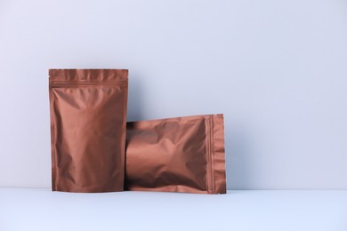 Photo of Two zipper stand-up pouches on light grey background. Mockup for design