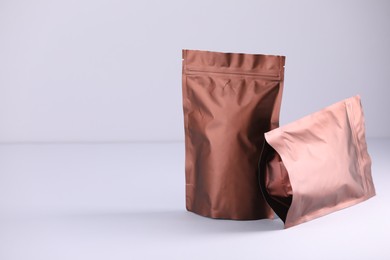 Photo of Two zipper stand-up pouches on light grey background. Mockup for design