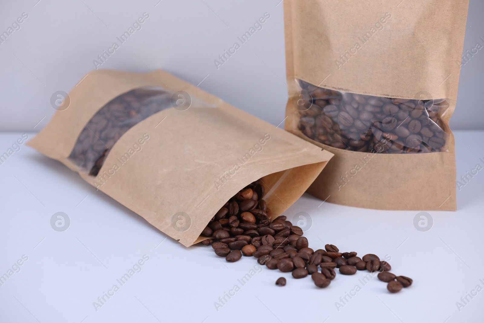 Zipper stand-up pouches with coffee beans on light grey background, closeup. Mockup for design Photo of Zipper stand-up pouches with coffee beans on light grey background, closeup. Mockup for design