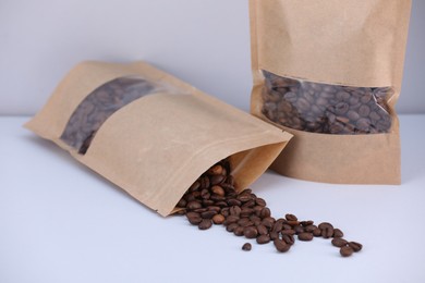 Photo of Zipper stand-up pouches with coffee beans on light grey background, closeup. Mockup for design