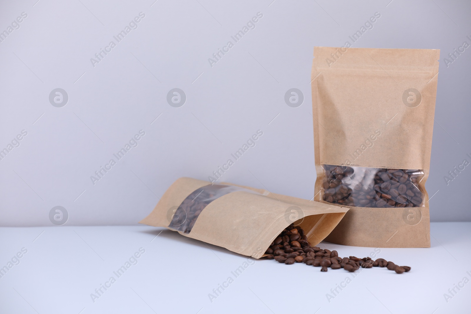 Zipper stand-up pouches with coffee beans on light grey background. Mockup for design Photo of Zipper stand-up pouches with coffee beans on light grey background. Mockup for design
