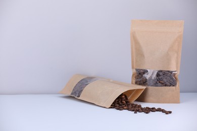 Photo of Zipper stand-up pouches with coffee beans on light grey background. Mockup for design