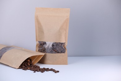 Photo of Zipper stand-up pouches with coffee beans on light grey background. Mockup for design