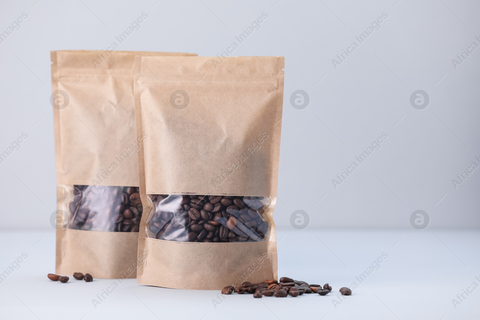 Zipper stand-up pouches with coffee beans on light grey background. Mockup for design Photo of Zipper stand-up pouches with coffee beans on light grey background. Mockup for design
