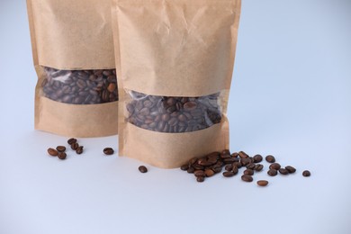 Photo of Zipper stand-up pouches with coffee beans on light grey background. Mockup for design