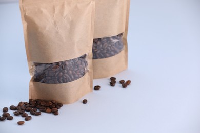 Photo of Zipper stand-up pouches with coffee beans on light grey background, closeup. Mockup for design