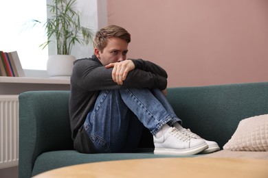 Photo of Man suffering from paranoia on sofa at home