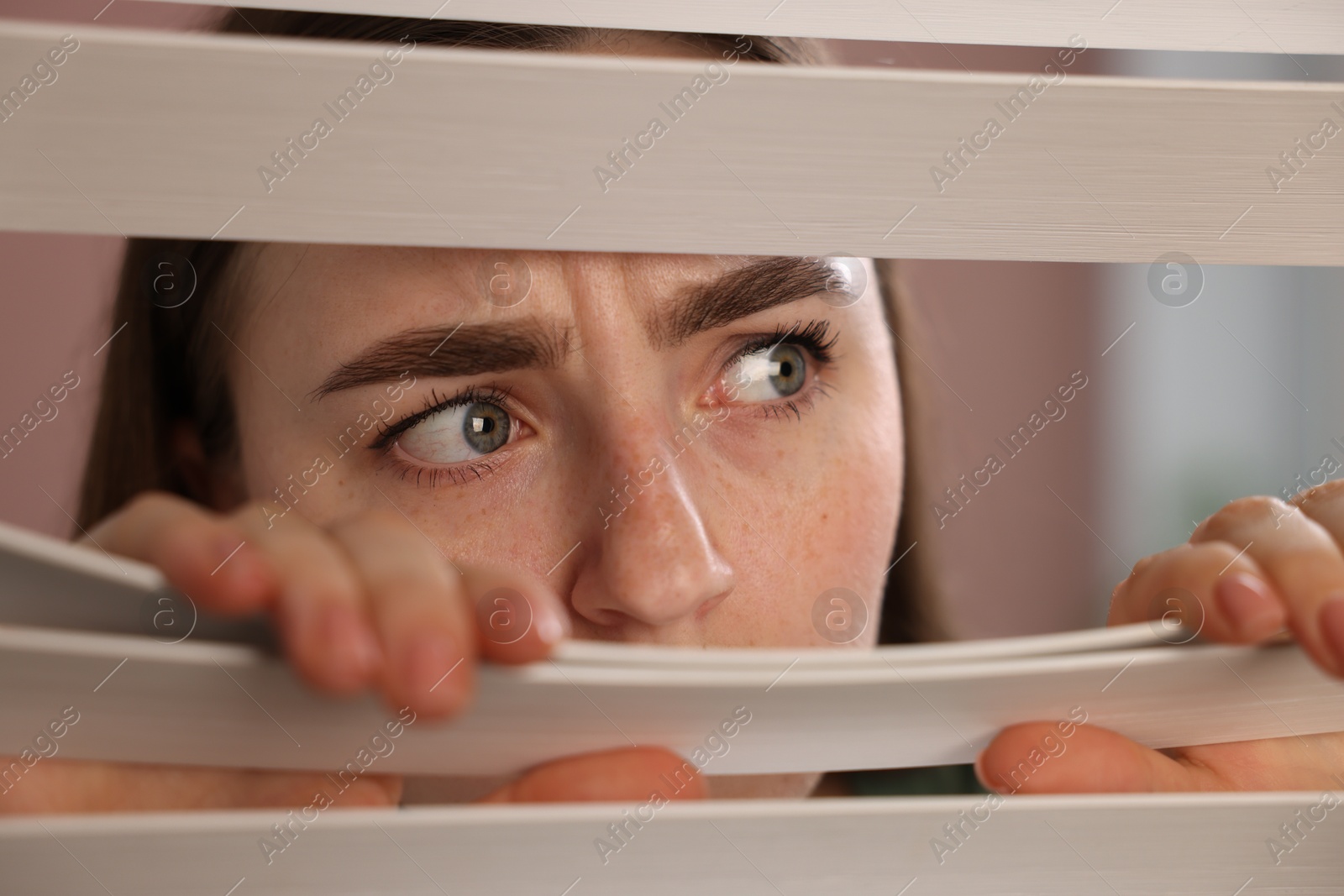 Paranoia. Worried woman looking through window blinds indoors, closeup Photo of Paranoia. Worried woman looking through window blinds indoors, closeup