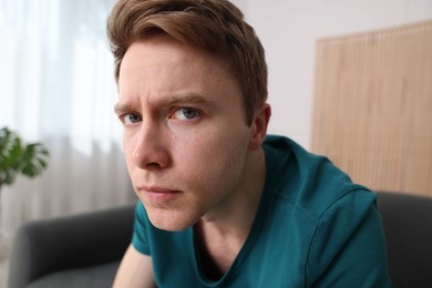 Photo of Scared man suffering from paranoia at home