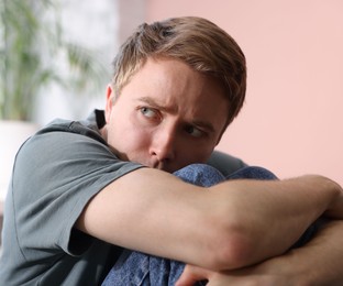 Photo of Scared man suffering from paranoia at home