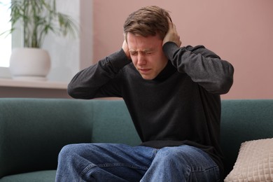 Photo of Man suffering from paranoia on sofa at home