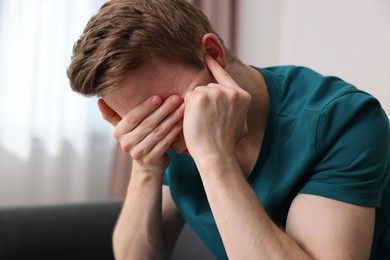 Photo of Scared man suffering from paranoia at home