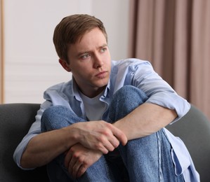 Photo of Man suffering from paranoia on sofa at home