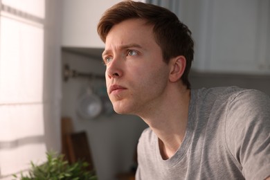 Photo of Young man suffering from paranoia in kitchen
