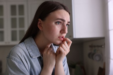 Photo of Worried woman suffering from paranoia in kitchen, space for text