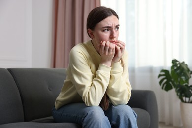 Photo of Worried woman suffering from paranoia on sofa at home