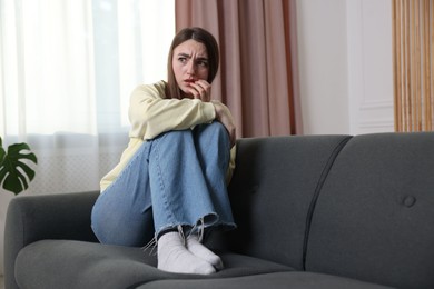 Photo of Worried woman suffering from paranoia on sofa at home