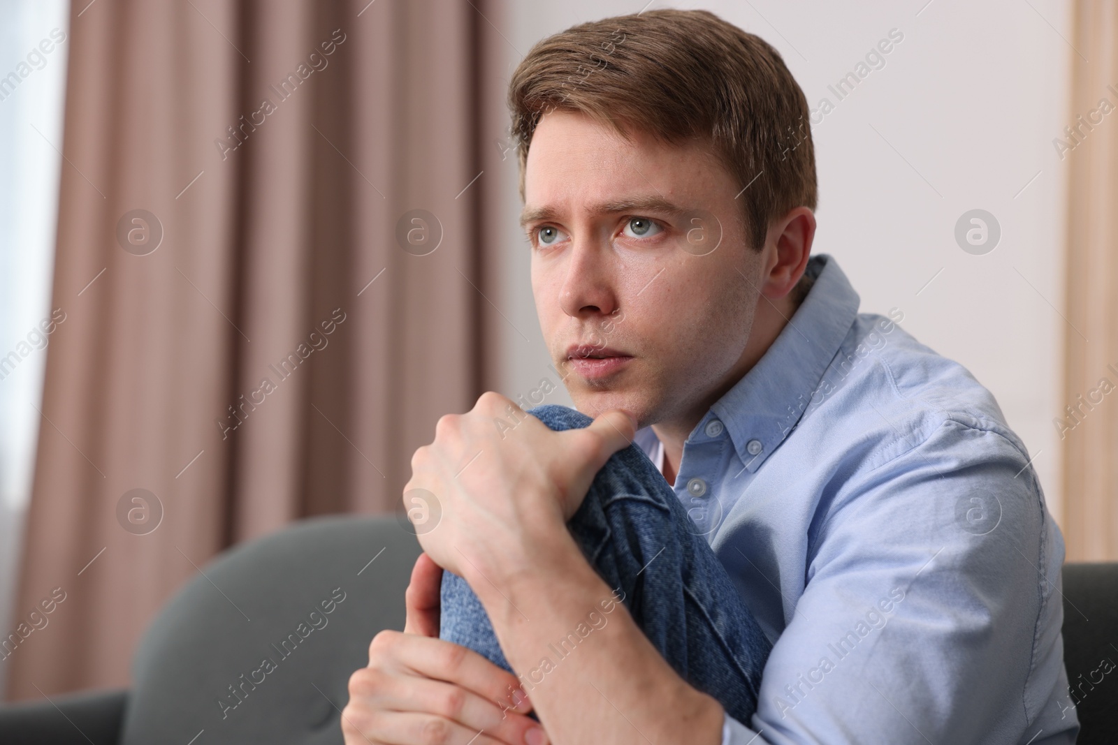 Man suffering from paranoia on sofa at home, space for text Photo of Man suffering from paranoia on sofa at home, space for text