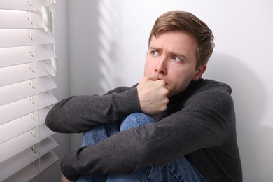 Photo of Man suffering from paranoia near window at home