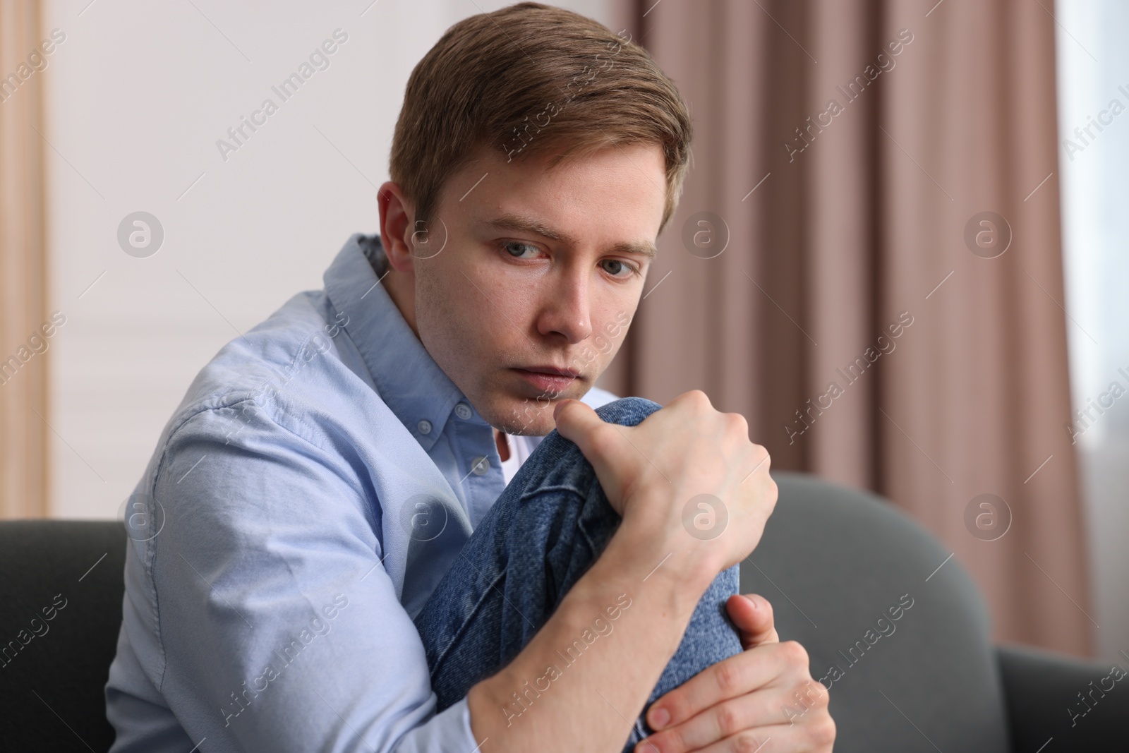 Man suffering from paranoia on sofa at home, space for text Photo of Man suffering from paranoia on sofa at home, space for text