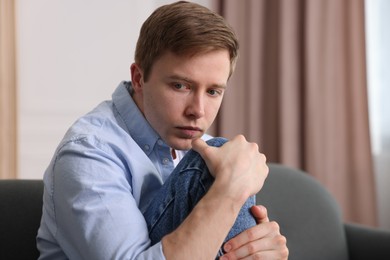 Photo of Man suffering from paranoia on sofa at home, space for text