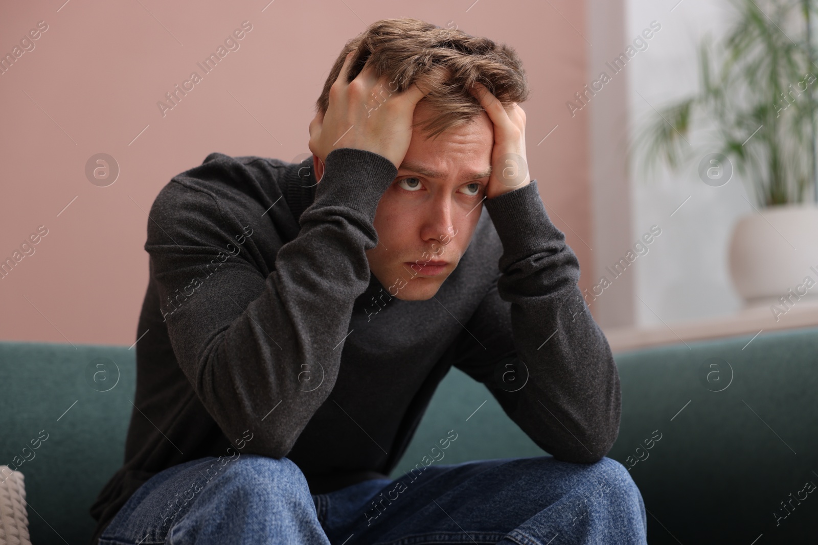 Man suffering from paranoia on sofa at home Photo of Man suffering from paranoia on sofa at home