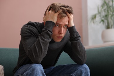 Photo of Man suffering from paranoia on sofa at home