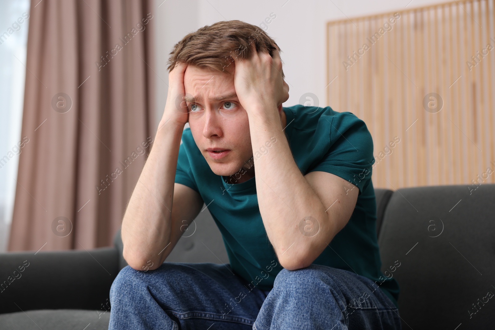 Man suffering from paranoia on sofa at home Photo of Man suffering from paranoia on sofa at home