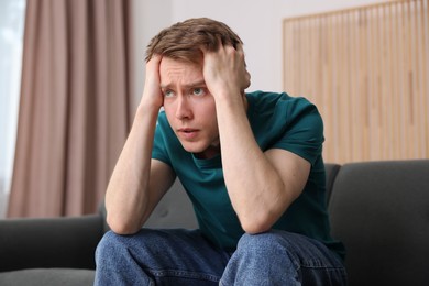 Photo of Man suffering from paranoia on sofa at home