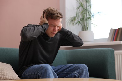 Photo of Man suffering from paranoia on sofa at home