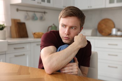 Photo of Man suffering from paranoia at table indoors