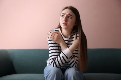 Photo of Worried woman suffering from paranoia on sofa indoors