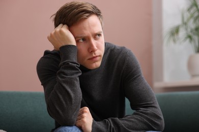 Photo of Man suffering from paranoia on sofa at home