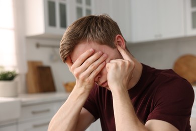 Photo of Young man suffering from paranoia in kitchen