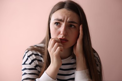 Photo of Worried woman suffering from paranoia near beige wall indoors
