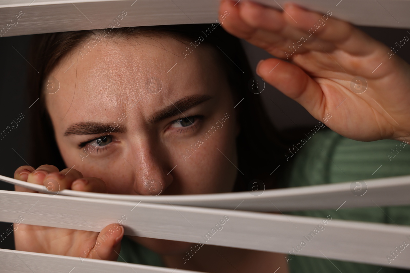Paranoia. Worried woman looking through window blinds indoors Photo of Paranoia. Worried woman looking through window blinds indoors