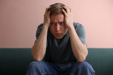 Photo of Man suffering from paranoia on sofa at home