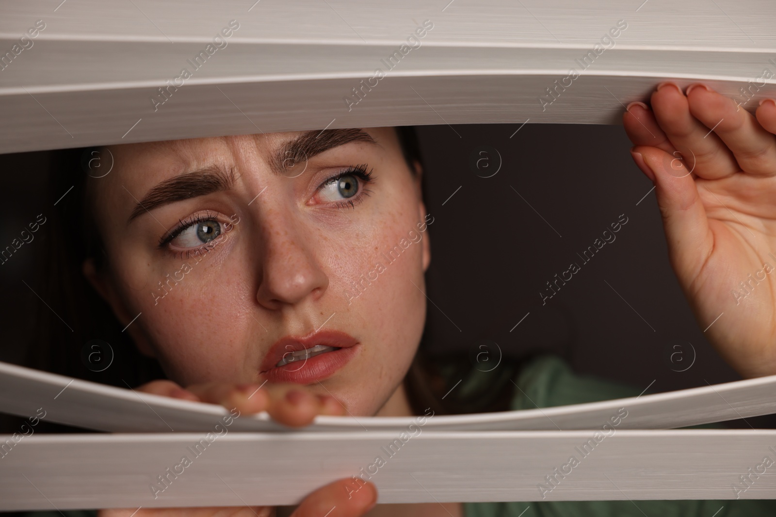 Paranoia. Worried woman looking through window blinds indoors Photo of Paranoia. Worried woman looking through window blinds indoors