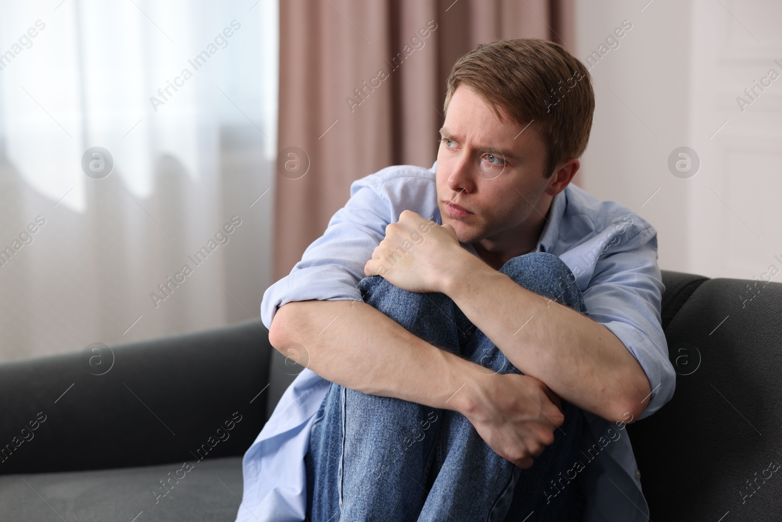 Man suffering from paranoia on sofa at home, space for text Photo of Man suffering from paranoia on sofa at home, space for text
