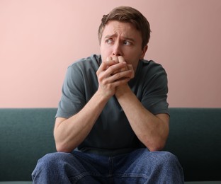 Photo of Man suffering from paranoia on sofa at home