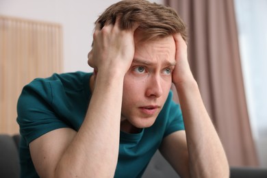 Photo of Scared man suffering from paranoia at home