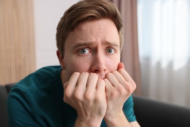 Photo of Scared man suffering from paranoia at home