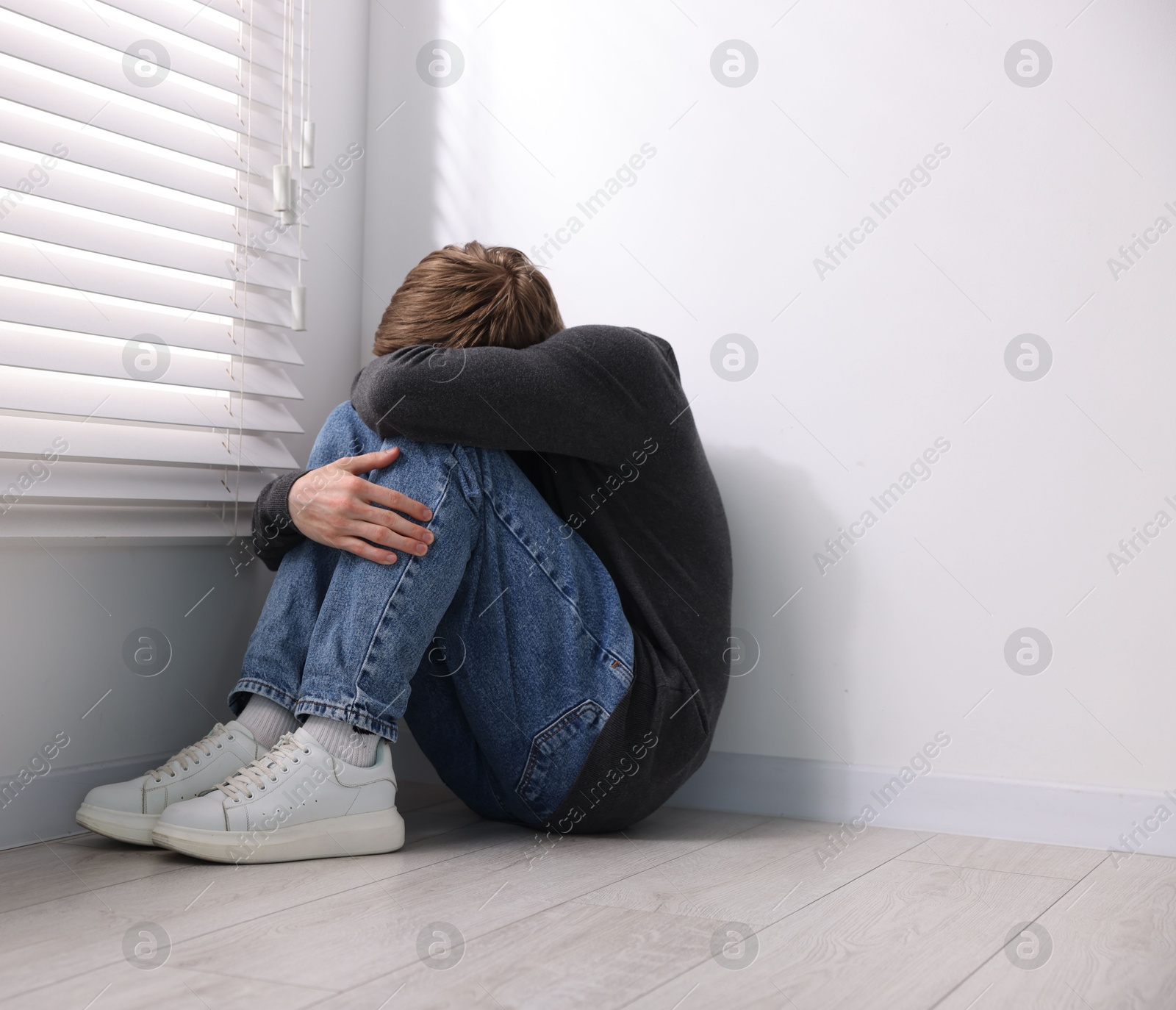 Scared man suffering from paranoia near window indoors Photo of Scared man suffering from paranoia near window indoors