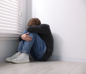 Photo of Scared man suffering from paranoia near window indoors